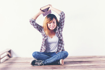 Wall Mural - Young hipster woman holding books and pointing up on isolated wh