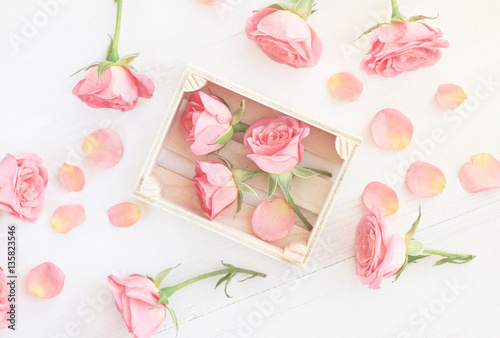 Little Light Pink Roses In Wooden Box And Petals Tered Over Little Light Pink Roses In Wooden Box And Petals Tered Over Table Soft White