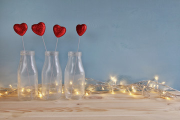 Glitter hearts in the glass vases on wooden table