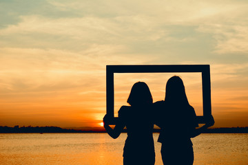 Wall Mural - Silhouette of women holding frame at the sky sunset concept valentine day