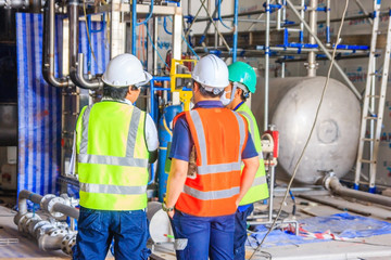 Engineer wear white helmet safty hold the blueprint on construction site with scaffolding background