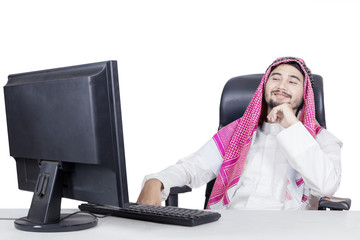 Wall Mural - Smiling arabian man looking at monitor