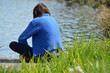 Młoda kobieta zamyślona nad brzegiem stawu/A young woman sitting pensive by the pond