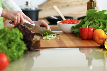 Closeup of human hands cooking vegetables salad in kitchen on the glassr table with reflection. Healthy meal and vegetarian concept