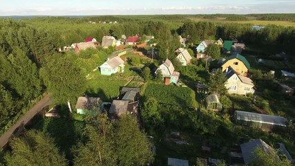 Wall Mural - Russian summer village with wooden houses at sunset. Flying over roofs. Forests of northern Karelia, Russia
