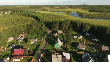 Wall Mural - Russian summer village with wooden houses. Flying over roofs. Evergreen forests of northern Karelia, Russia
