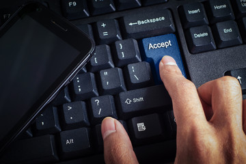 business concept shows the smartphone as well as the fingers that press ACCEPT on the keyboard