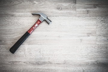 Red hammer on wooden floor, interior construction tool or home fixing renovation concept, dark tone abstract with vignette effect