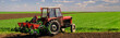 Farmer with tractor sowing on agricultural fields on sunny spring day