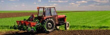 Farmer With Tractor Sowing On Agricultural Fields On Sunny Sprin