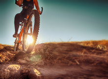 A Woman Riding A Bicycle Down A Dirt Trail With Big Rocks In The Hills