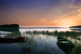 Fototapeta  - Rowing boat floating on the calm depths of the  Lake Lasmiady. Just the sun rises.  Masuria, Poland.