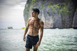 © theartofphoto - Half body shot of a handsome young man standing on a beach in Phuket Island, Thailand, shirtless wearing boxer shorts, showing muscular fit body