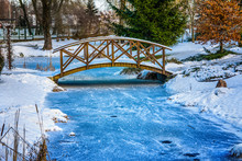Winter In The Park. Snowy, Wooden Bridge Over Frozen Pond. Poland.