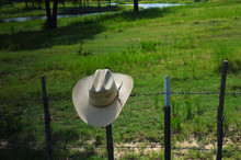 Straw Hat On Fence Post In The Country Rural Scenery.
