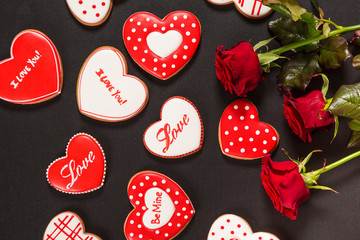 Beautiful gingerbread heart and red roses on a black background. Postcard for Valentine's day, March 8, mother's day or Wedding.