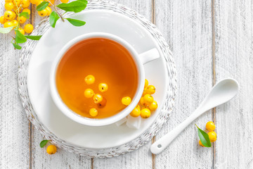 Wall Mural - Fresh warmer herbal hawthorn tea with fresh berries in a white cup on wooden background, alternative medicine