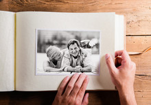 Hand Holding Photo Album With Pictures Of Senior Couple. Studio