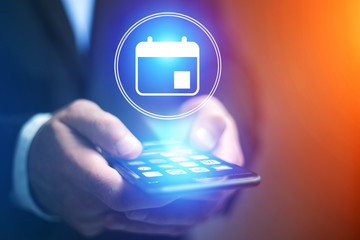 Poster - businessman hand holding mobile phone with calendar icon