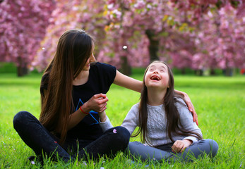 Wall Mural - Happy beautiful young woman with girl in blossom park with trees and flowers.