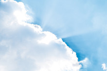 White Cloud Against Blue Sky With Rays Of Light For Background