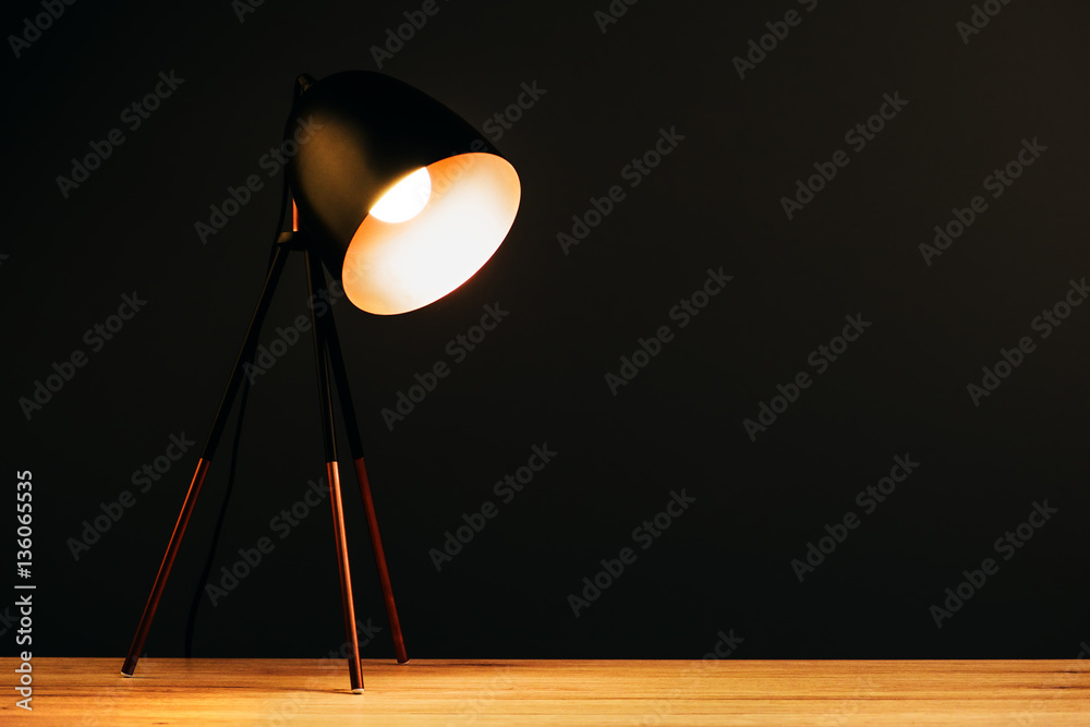 Desk lamp on table in dark office - obrazy, fototapety, plakaty 