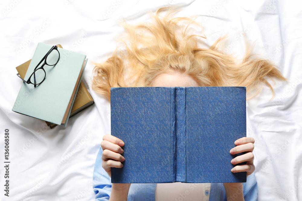 Girl reading book on bed