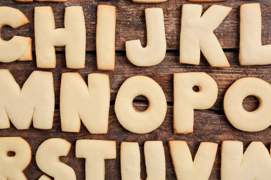 Cookie alphabet on wooden background, closeup
