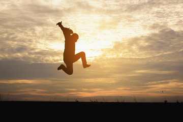 A silhouette of man  jumping in the sunset background.