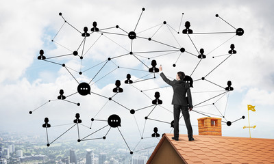 businessman on house roof presenting networking and connection concept. mixed media