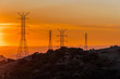 Los Angeles skyline at sunset viewed from afar through power lines.