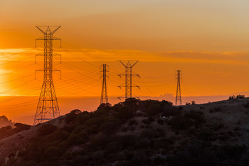 Wall Mural - Los Angeles skyline at sunset viewed from afar through power lines.