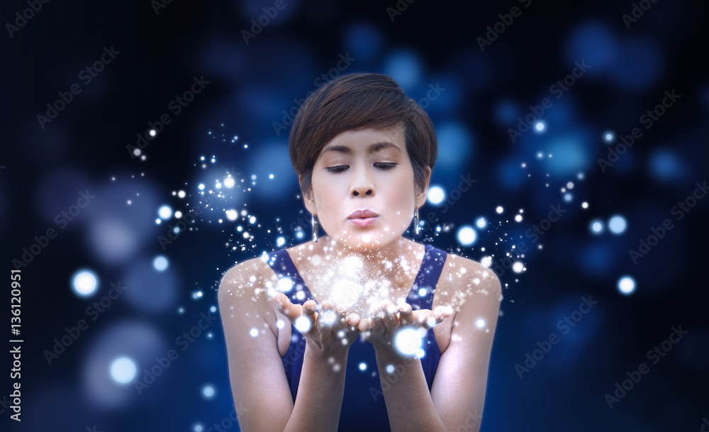 Beauty woman blowing magic dust and glowing bubbles from her hands. Magical Concept. Isolated on dark blue background - obrazy, fototapety, plakaty 
