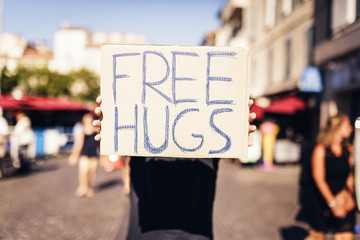man holding free hugs sign in european city