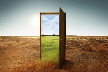 Open wooden door to the new world with green environment