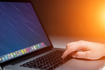 Hand typing on a keyboard of laptop with operating system screen on background