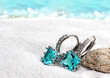 Jewelry earrings with aquamarine on sand beach background, soft