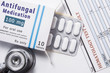 © shidlovski - Antifungal drug. Open paper packaging box of medication with name group of drug Antifungal, blister with pills, next to stethoscope and blood test results. Concept for treatment of fungal diseases