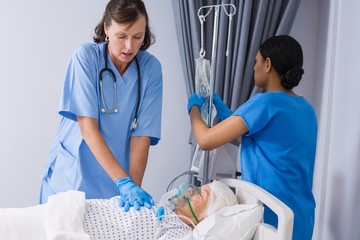 Canvas Print - Doctor and nurse treating senior patient in ward