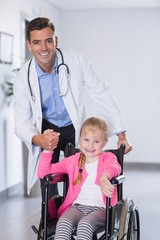 Wall Mural - Portrait of doctor pushing girl in wheelchair 