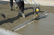 Smoothing fresh concrete with gas powered vibrating screed machine