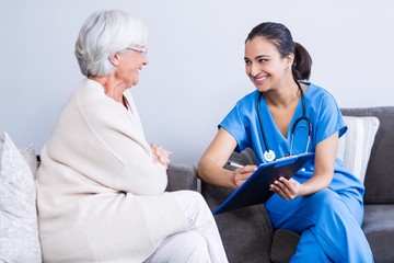 Wall Mural - Doctor and senior woman discussing on clipboard