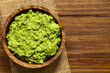 Avocado dip or guacamole in wooden bowl, photographed overhead with natural light (Selective Focus, Focus on the avocado dip)