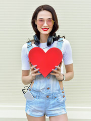 Wall Mural - Beautiful smiling woman holding a red heart. Fashion portrait st