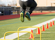 Male athlete jumping over yellow hurdles