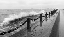 Waves Crashing Over Pier Pillars And Chain At Shoreline