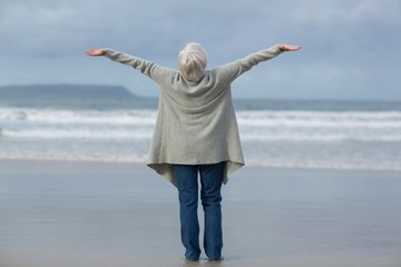 Senior woman standing with arms outstretched on the beach