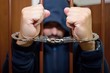 © Branislav - Abstract. Hands of the prisoner on a steel lattice close up. Prison, man in handcuffs.