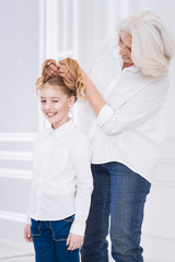 Poster - Positive loving aged woman playing with hair of her granddaughter