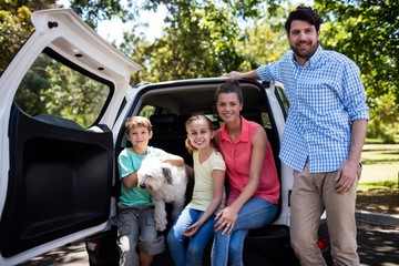 Wall Mural - Happy family sitting in car trunk with their dog